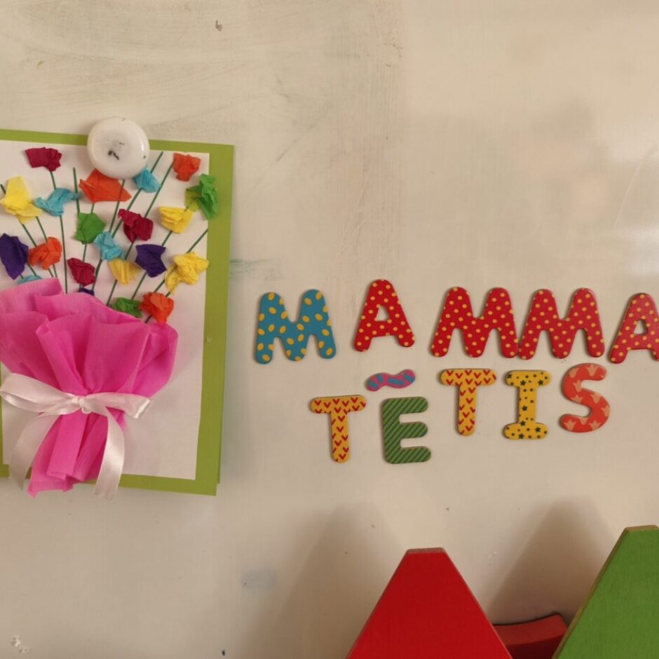 ATTĒLOS NO TĀFELES. PIELIKTS BĒRNU VEIDOTS RADOŠAIS DARBIŅŠ ZIEDI MĀMIŅAI UN NO MAGNĒTISKAJIEM BURTIEM IZVEIDOTI VĀRDI MAMMA TĒTIS.